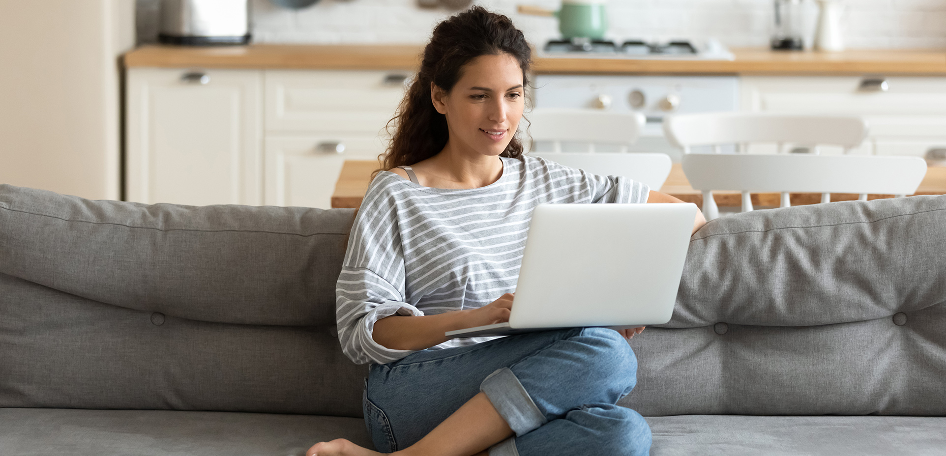 Frau sitzt auf Couch mit Laptop